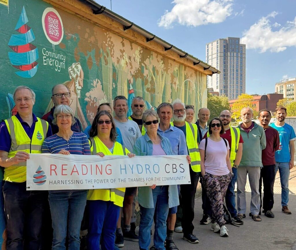A group of people standing in front of the Reading Hydro turbine house, holding a sign that reads 'Reading Hydro CBS'